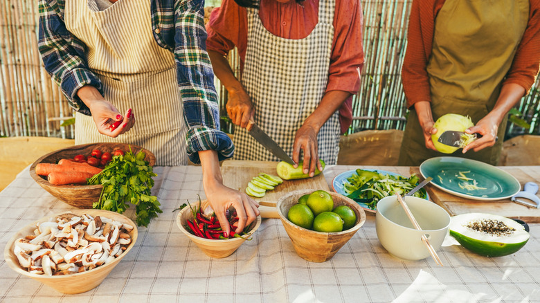 Three women chopping vegetables at a table in Asia