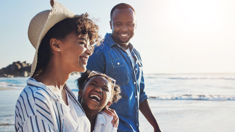 Parents laughing with their daughter on the beach