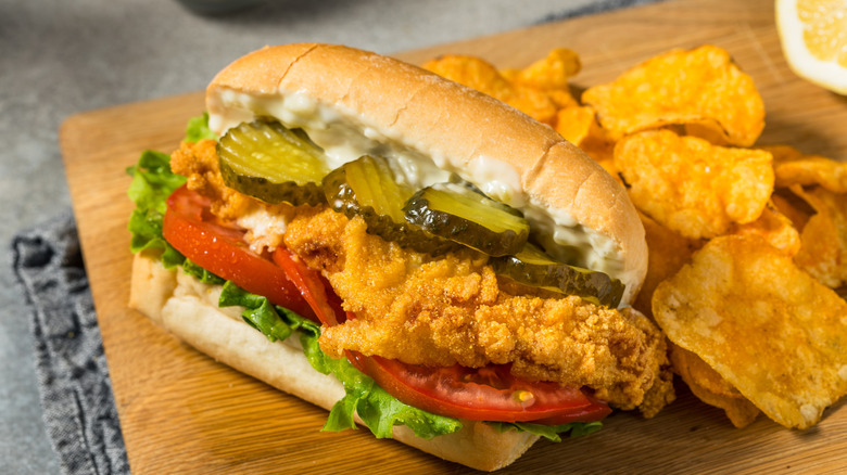 New Orleans catfish po'boy sandwich on a wooden board with chips