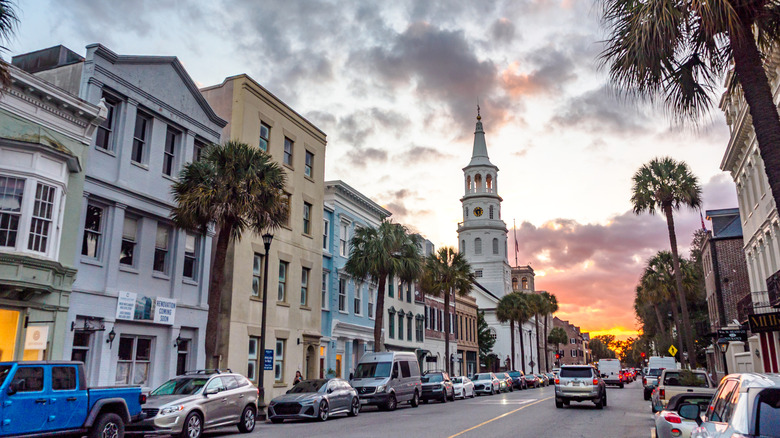 Historic downtown in Charleston, South Carolina with rows of stores, a church, and palmetto trees lining the road