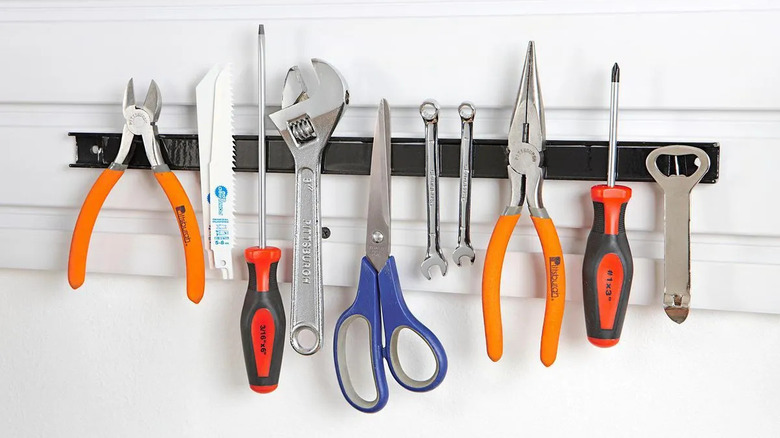 A magnetic strip on the wall holds scissors and other tools