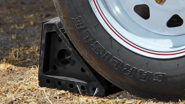 A Haul-Master brand rubber wheel chock next to a tire