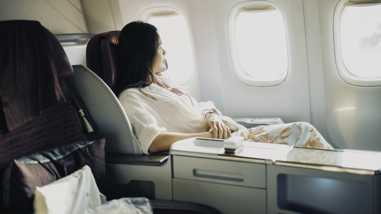Woman relaxing in business class seat on a plane looking out the window