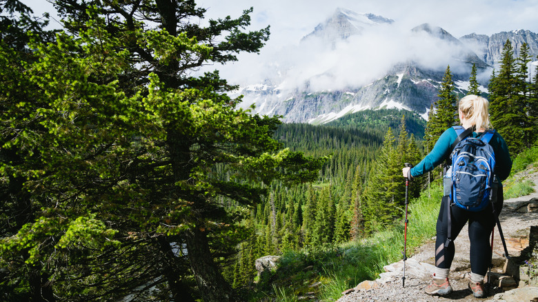 Blonde woman hiker takes a moment to enjoy the scenery along the Grinnell Glacier Hike in Glacier National Park, Montana