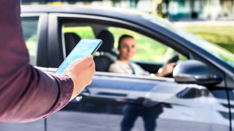 Vehicle pulling up next to someone holding a phone