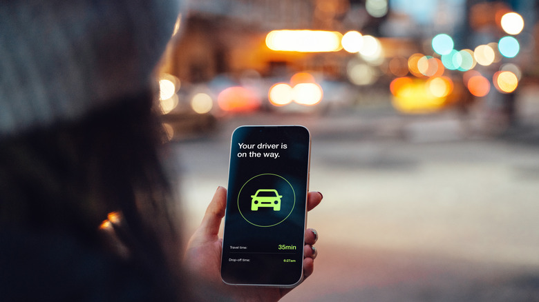 Someone looking at a rideshare app that states their driver is on the way