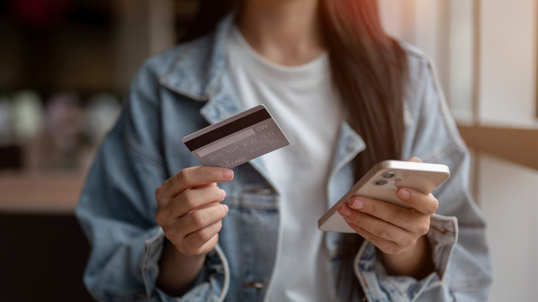 Woman holding a credit card in one hand and a phone in the other