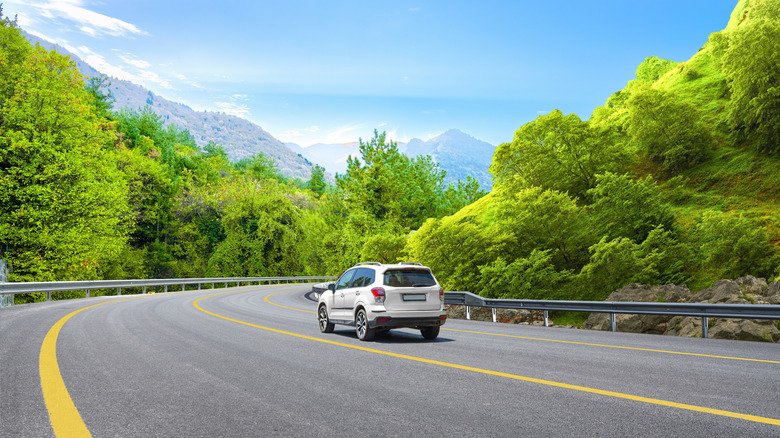 Car on road surrounded by trees and mountains