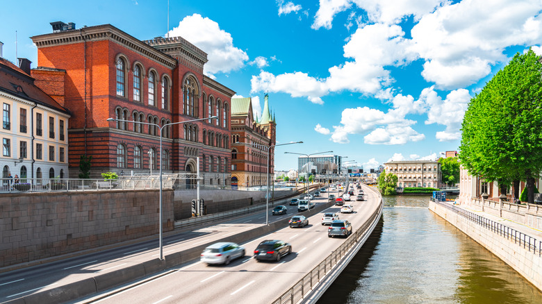 Cars on road with historic buildings and canal