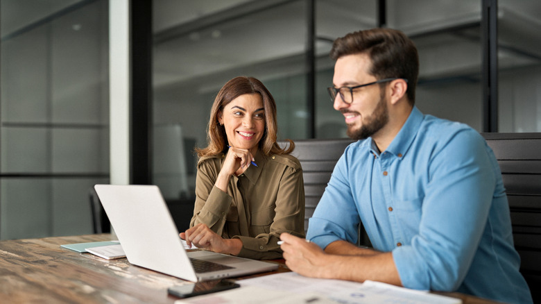 Two people sitting at a desk, using a laptop computer