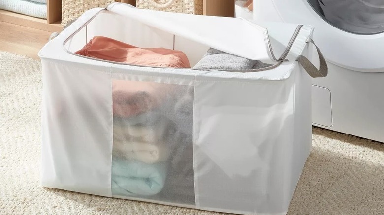 A soft-sided, zippered storage container with linens in it
