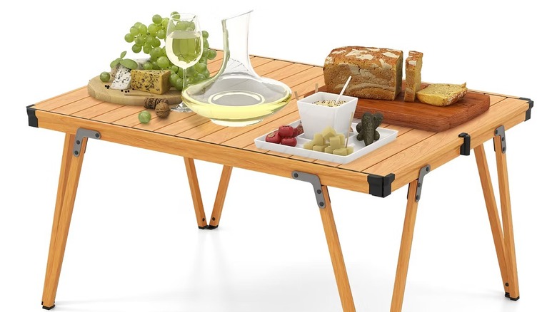 A foldable wooden camp table with snacks on top of it