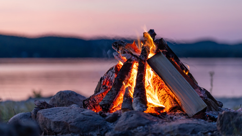 A campfire in front of a lake at dusk