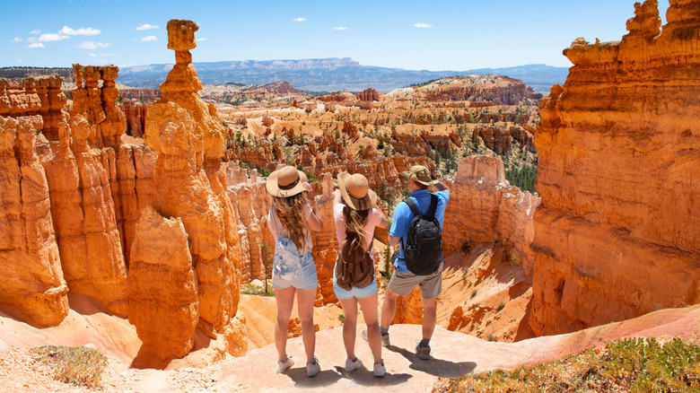 People standing next to the Thor's Hammer hoodoo, looking out at Bryce Canyon National Park