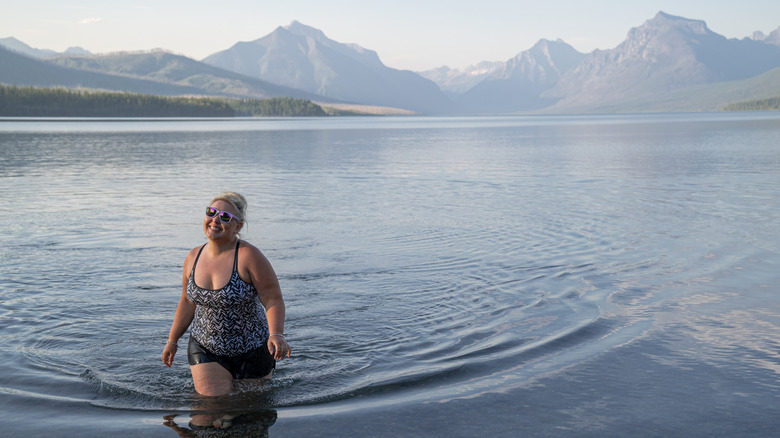A blonde woman wades into Lake McDonald in Glacier National Park
