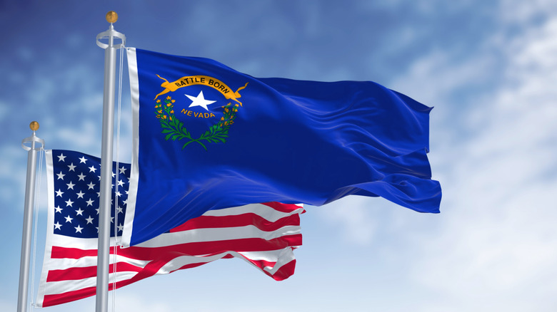 The state flag of Nevada waving in the wind with the U.S. flag in the background
