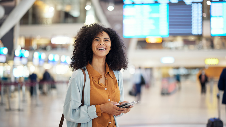 A Black woman smiles in an airport terminal