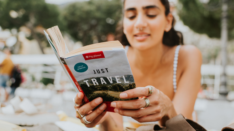 A woman reading a travel guide on the beach