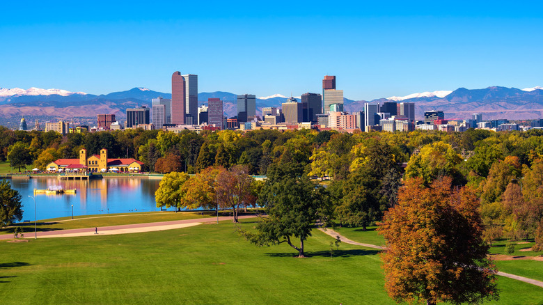 Aerial view of Denver's City Park with lake in front of dramatic skyline and mountains