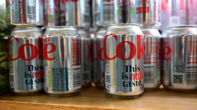 Classic Diet Coke cans sit on a shelf