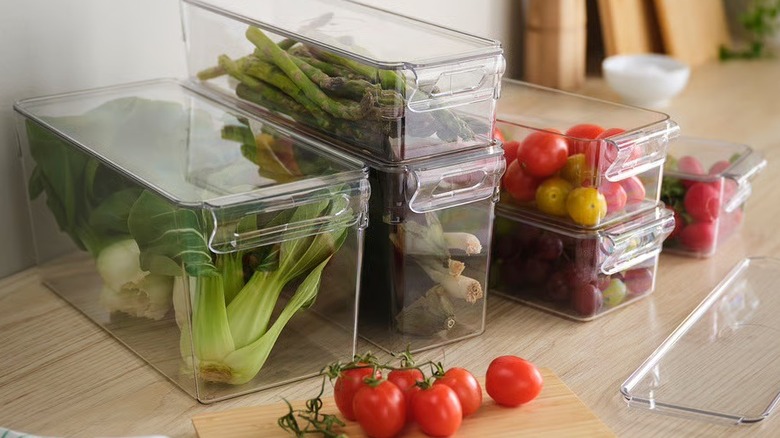 Produce stored on a countertop in clear plastic bins with lids