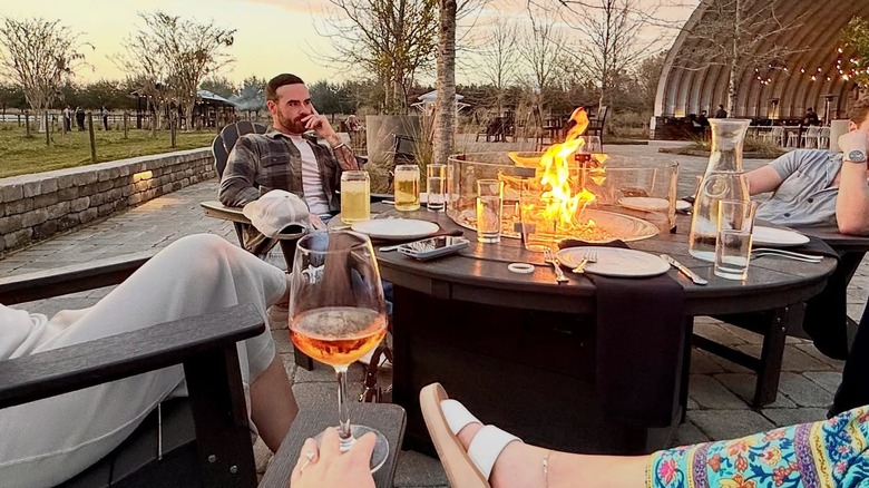 people seated at an elegantly laid outdoor table with a fire pit at the center