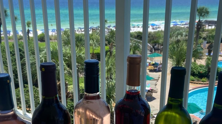 six bottles of wine on a balcony overlooking the beach