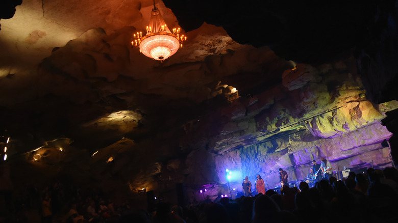 a chandelier hanging from the cave ceiling above a performance