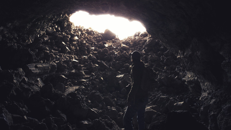 a person inside a cave facing an exit with blinding light