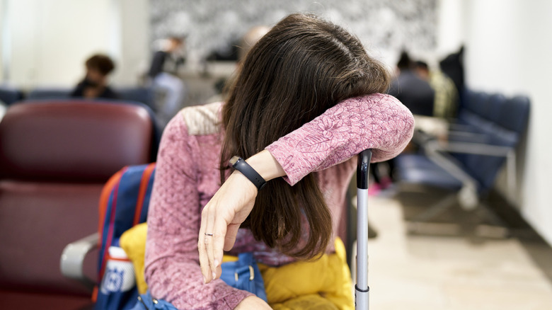 Exhausted woman laying her head on her luggage