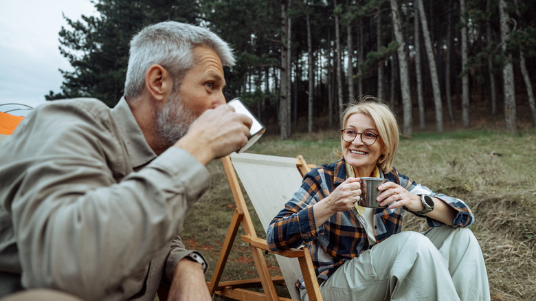 Mature couple enjoying hot drinks while camping together in nature