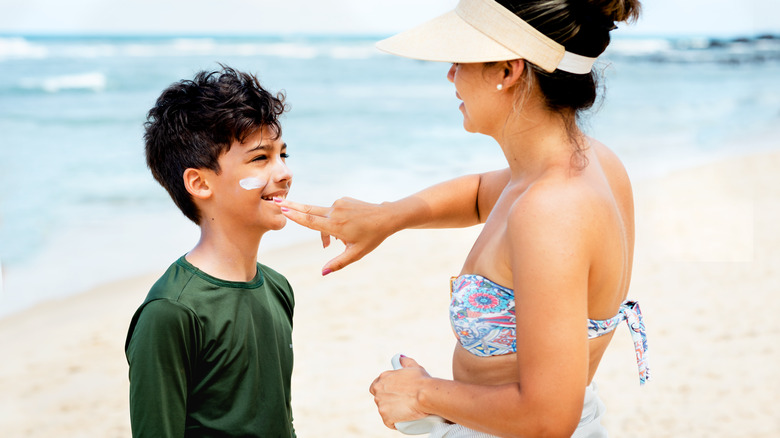 Woman applying sunblock on son