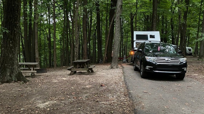An SUV and a small camper trailer in a wooded campsite at Brown County State Park, Indiana