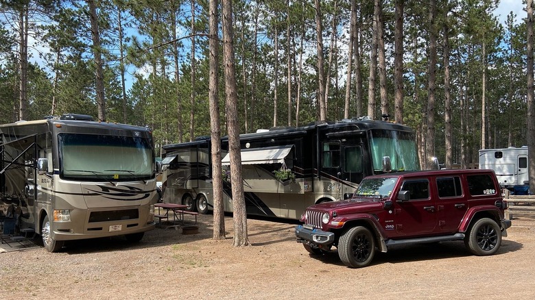 Motorhomes and a Jeep parked under trees at Hayward KOA Holiday, Hayward, Wisconsin