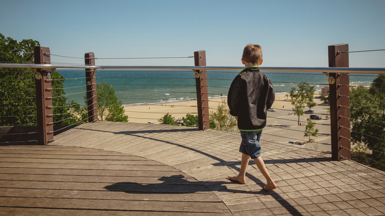 Boy walking along Indiana Dunes State Park Bird Observatory, looking out at Lake Michigan