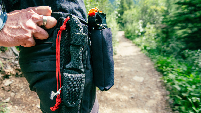 A man on a walking trail with a utility belt with a knife and bear spray