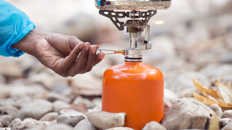 close up of hand adjusting an orange fuel cannister