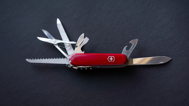 Red swiss multifunction knife on black background. Victorinox Swiss Army knife. Copy space.