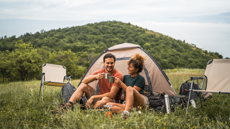 couple in love sit on the grass enjoy camp with coffee and talk