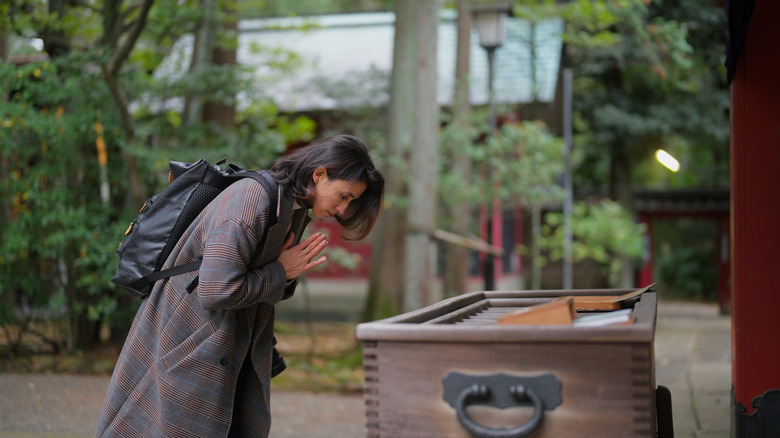 Female tourist bowing at a shrine before entering