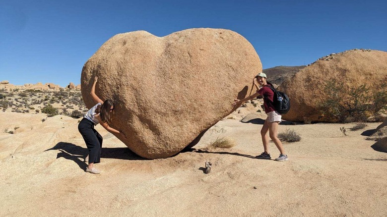 Two young women pose with Heart Rock in Joshua Tree National Park.