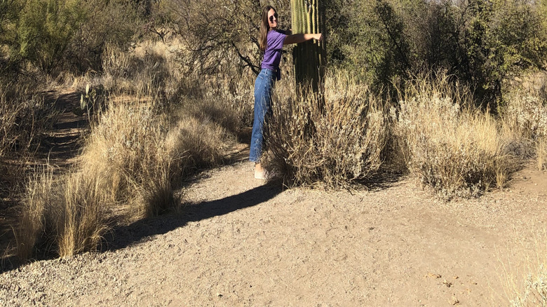A young woman embracing a saguaro cactus in Saguaro National Park, Arizona.