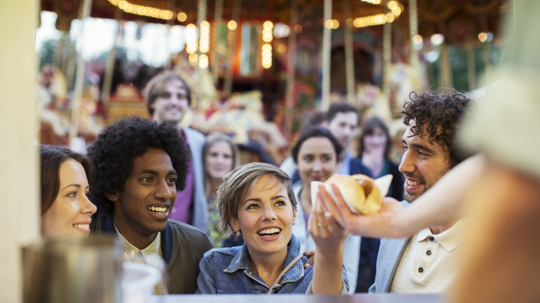 Person buying food at crowded amusement park