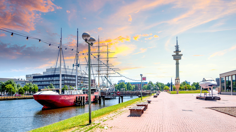 Tall ships are moored next to a brick walkway on the sunny waterfront in Bremerhaven, Germany