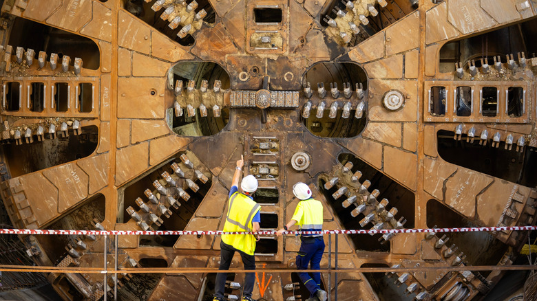 Workers inspect and repair a tunnel boring machine.