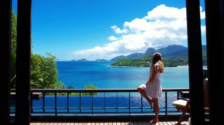 A woman stands on a balcony next to a plunge pool at Anantara Maia Seychelles Villas