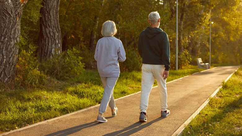 An older couple walking through woods