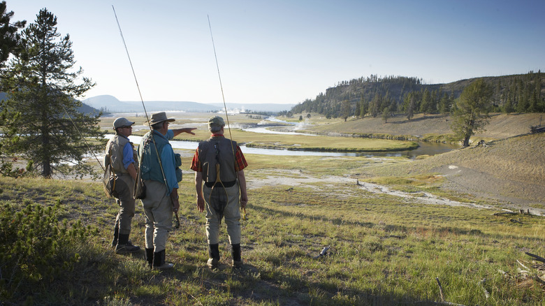 A group of men stand with fishing poles