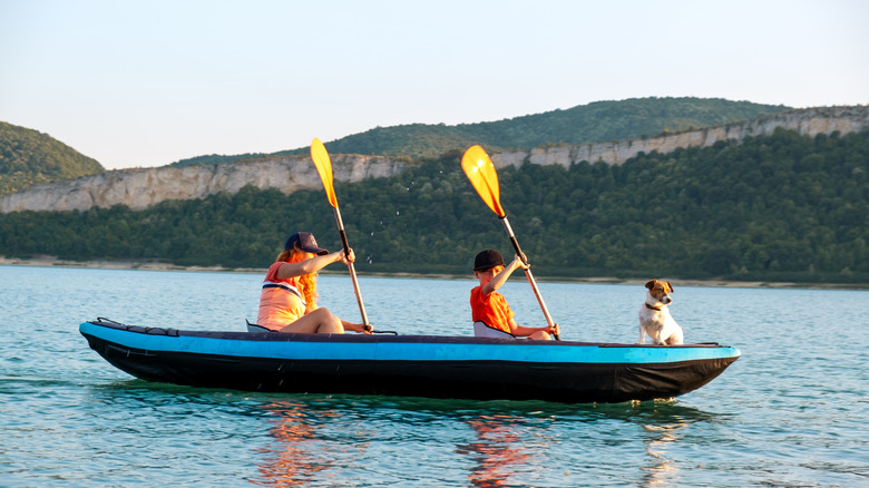 Two people with a dog in an inflatable kayak