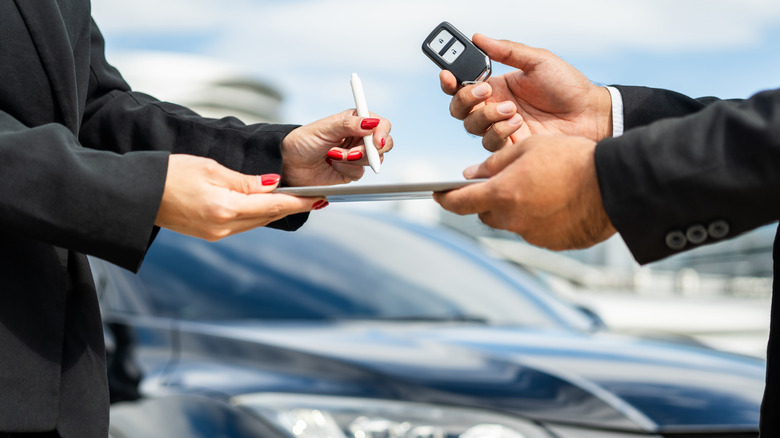 A woman being handed a key to a rental